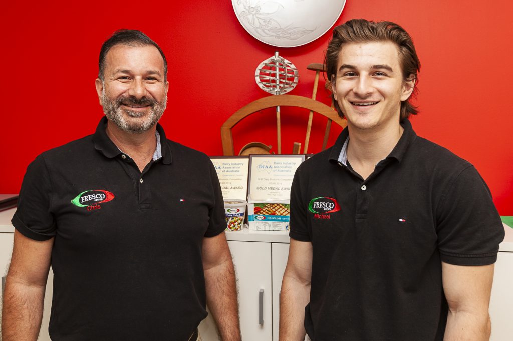 Two smiling men in front of a bright red wall | featured image for About Fresco Cheese.