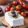 A block of fetta cheese with two olives and thyme. | Featured image for Fresco Cheese.