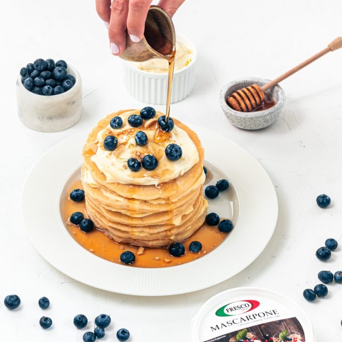 A stack of pancakes with marscarpone being drizzled with syrup. | Featured image for What is Mascarpone Cheese blog for Fresco Cheese.