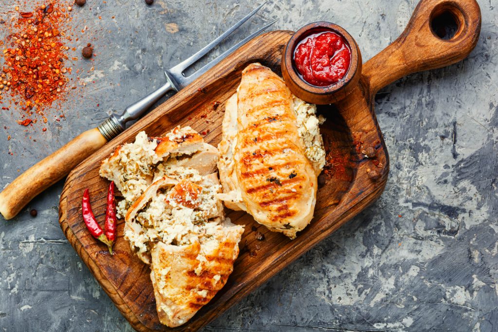 Chicken breasts with crumbled feta and peppers on a wooden serving plate | Featured image for What is Feta Cheese Blog at Fresco Cheese.